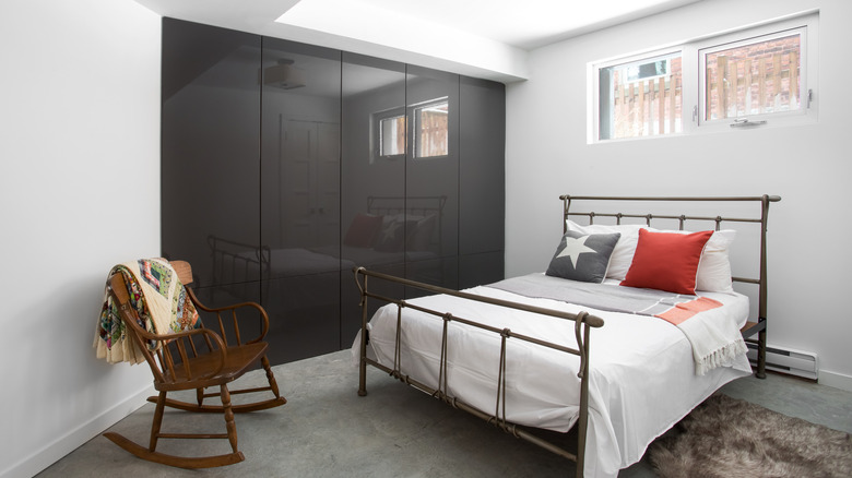 A basement bedroom with a queen-sized bed, rocking chair and closet