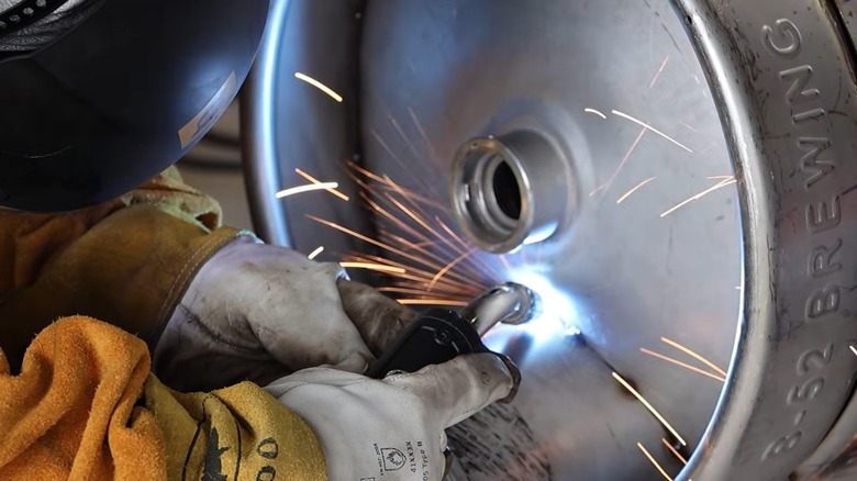 Person welding two kegs together