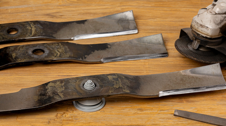 Several old lawn mower blades and an angle grinder