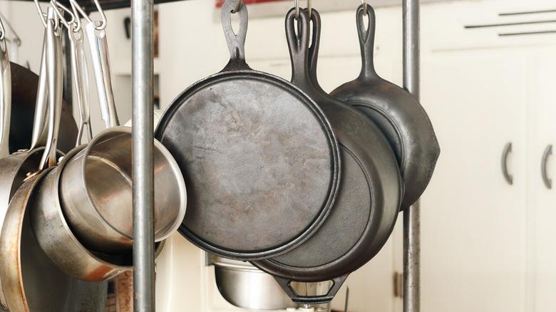 Cast iron pans hanging from metal storage shelf in kitchen