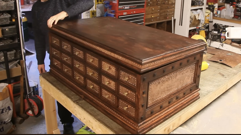A dark wood apothecary chest on a workshop table.