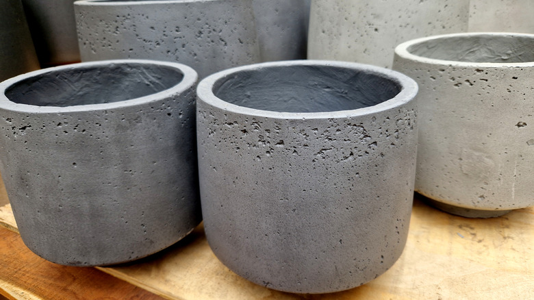 An assortment of cement planters standing on a wooden table.