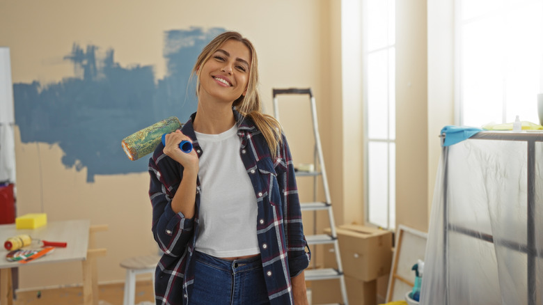 Smiling young woman painting her new apartment