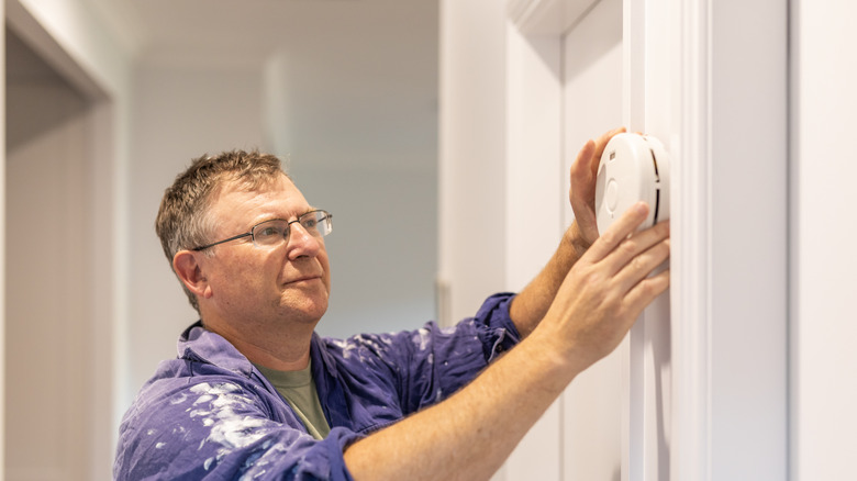 Man installing a smoke detector on wall