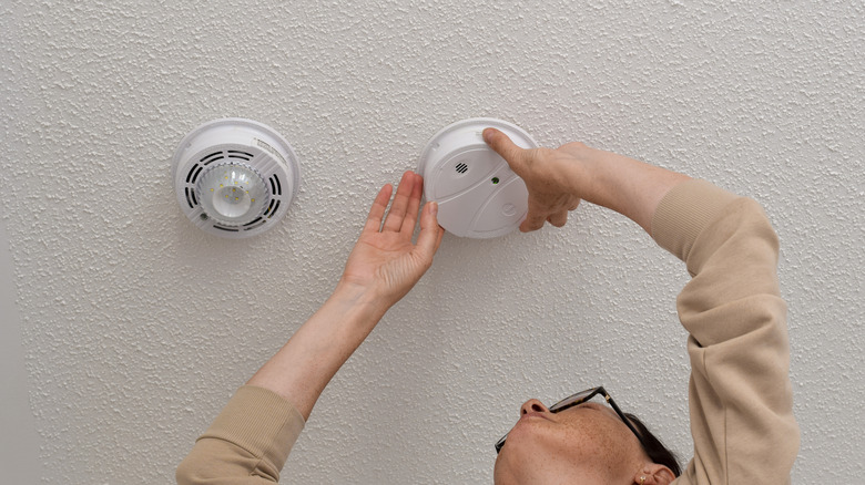 Woman reaching up to adjust smoke detector