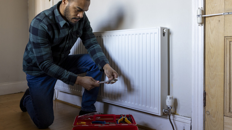 A man works on repairing a radiator in an apartment