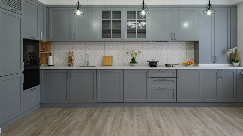 A stylish monochromatic kitchen with gray cabinets and white backsplash