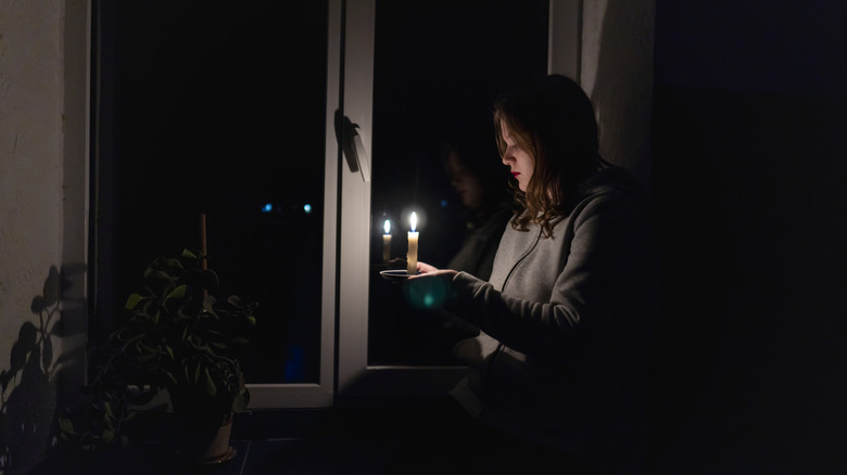 An African American man applies caulk around a window frame.