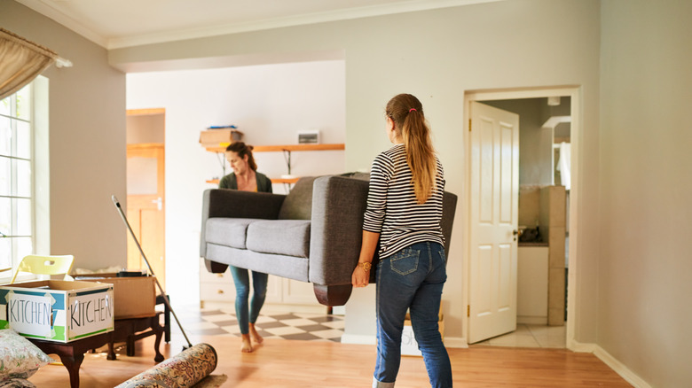 Two women carrying a couch