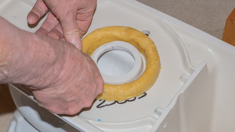 Man replacing toilet ring