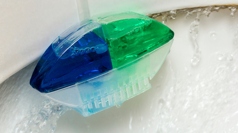 Water flowing over a blue and green hanging toilet deodorizer