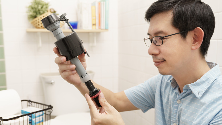 Man holding and looking at a new fill valve