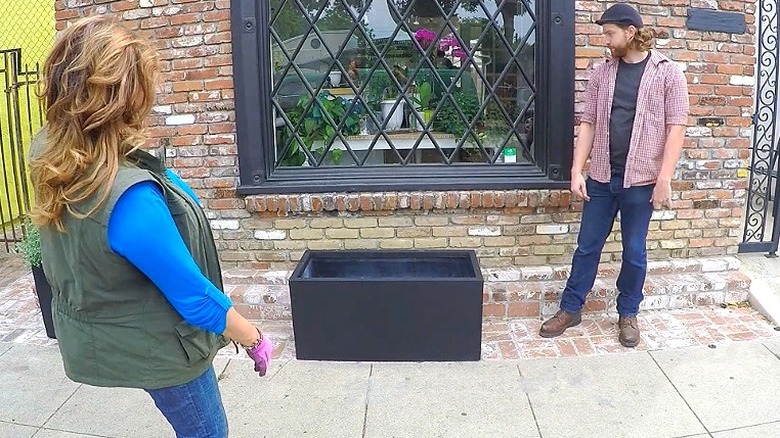 Shirley Bovshow and her assistant take a look at a rectangular planter in front of the brick building
