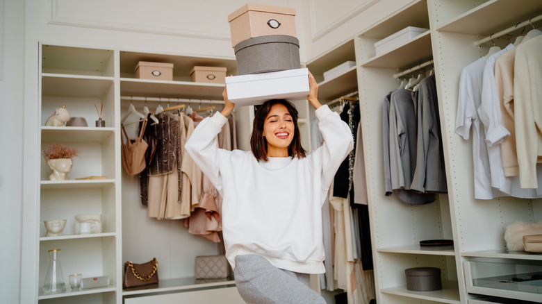 Woman inside a closet holding boxes on her head
