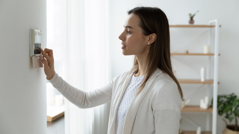woman adjusting a thermostat