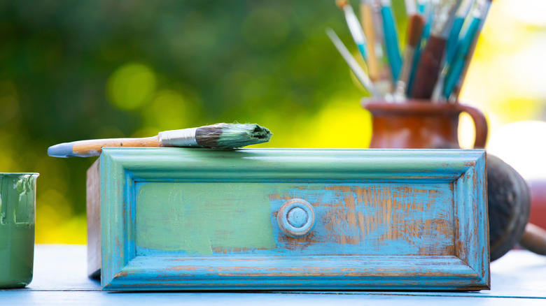 Close up of a wooden dresser drawer painted blue and green