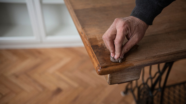 Close up of a person waxing a wooden table