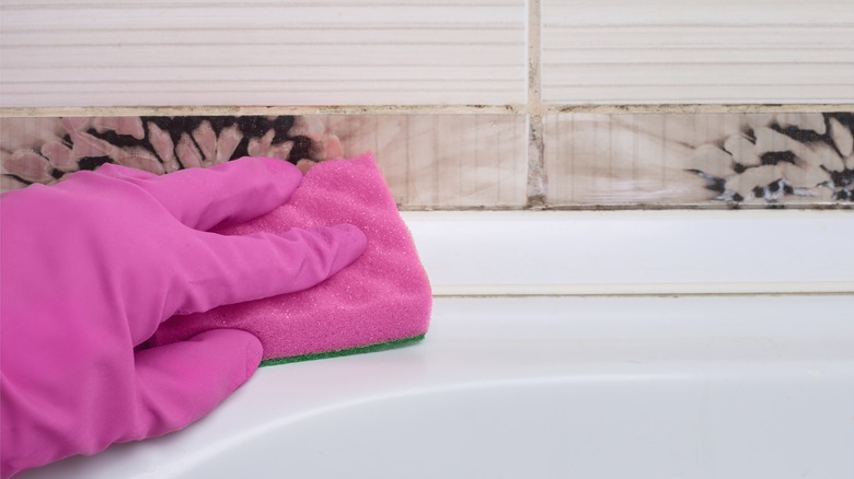 gloved-hand wiping shower with sponge