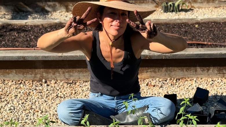 Joanna Gaines sitting on gravel path in garden
