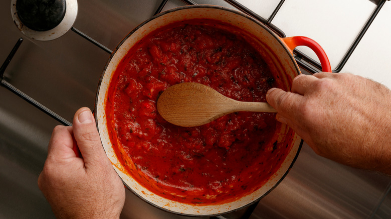 stirring sauce with wooden spoon