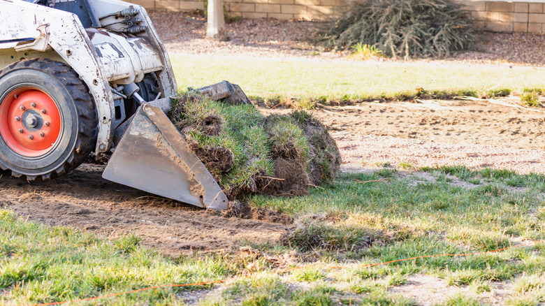 Bulldozer digging up lawn patches