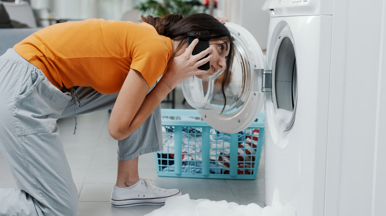 Woman on phone by leaking washer