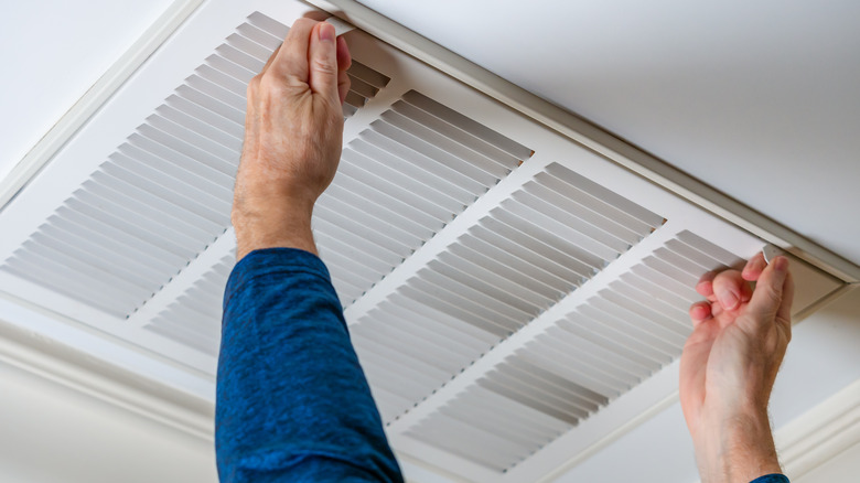 Person removing ceiling air vent cover