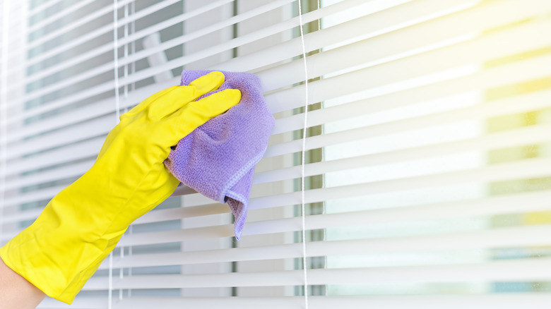 hands cleaning window blinds