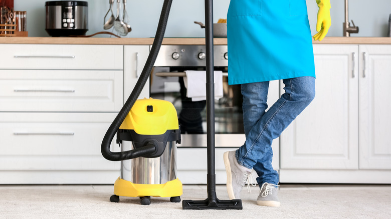 person with vacuum in kitchen