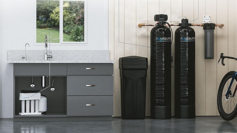 An Aquasure water softening system is installed in a garage next to a utility sink