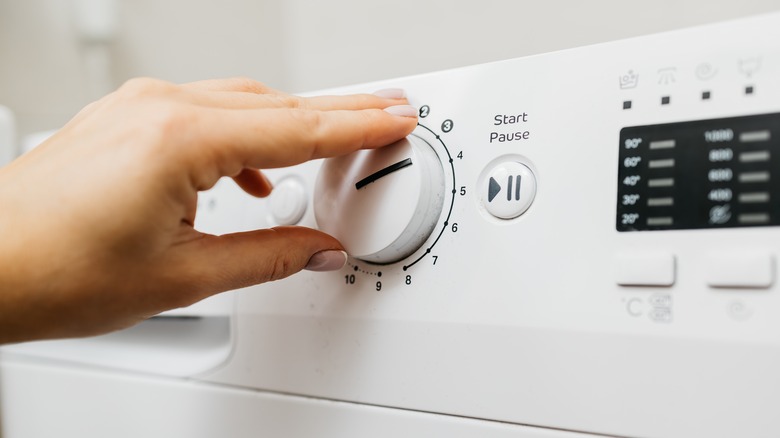 Woman turning clothes dryer on