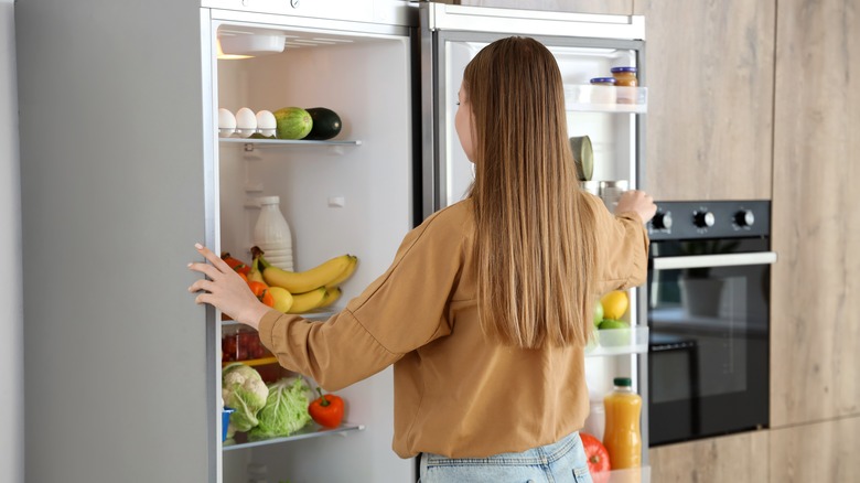 Woman standing in front of an open refrigerator door
