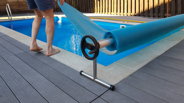 man unrolling pool cover