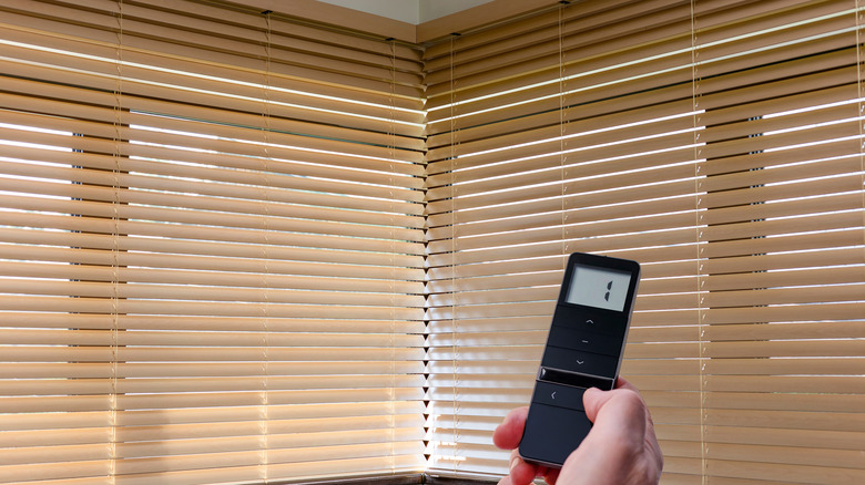 Wooden-slat smart blinds being controlled by a remote.