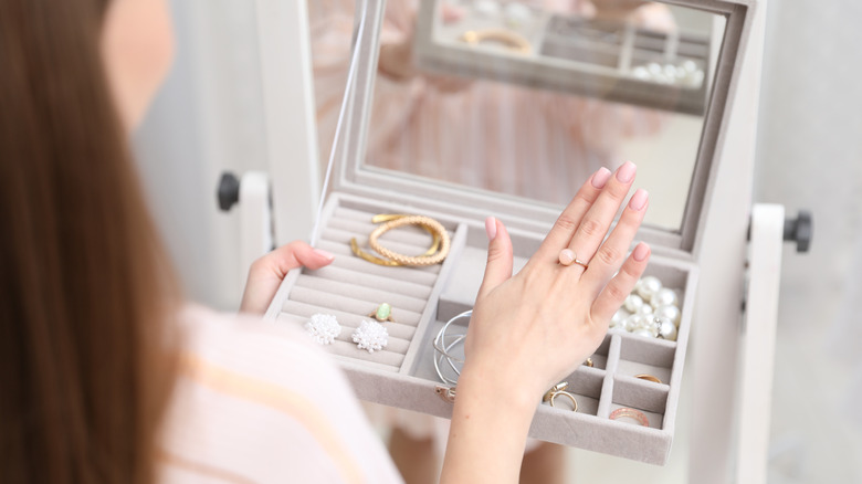 person looking at their jewelry in a box holding up her hand with a ring