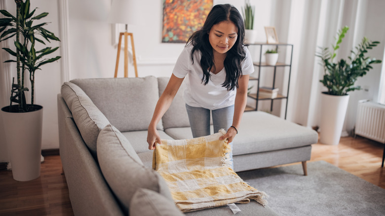 woman folding blanket on couch