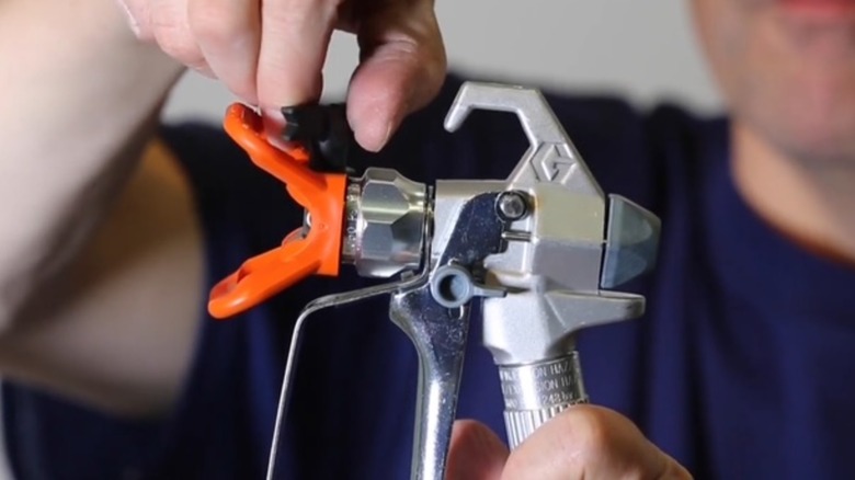 Turning nozzle backward on paint sprayer