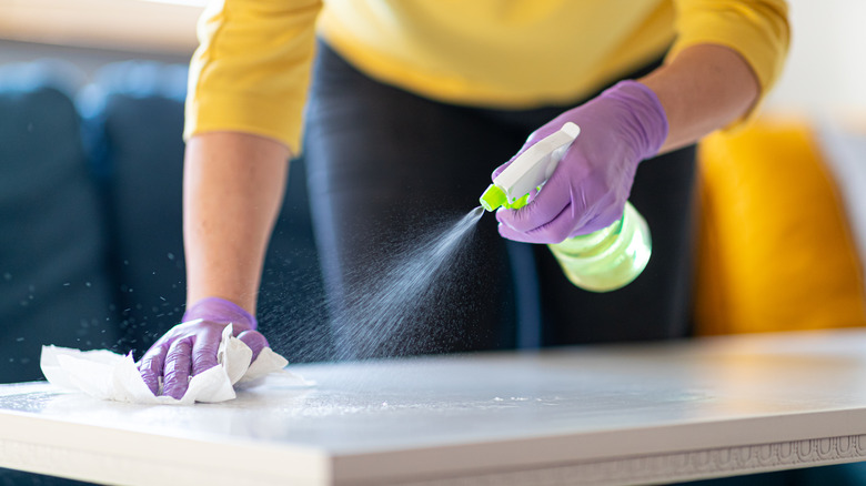 Person with gloves sprays cleaner