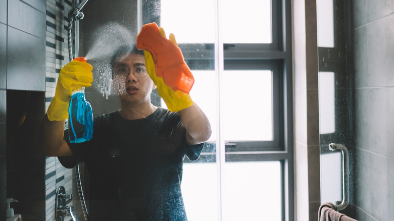 Man cleaning shower glass