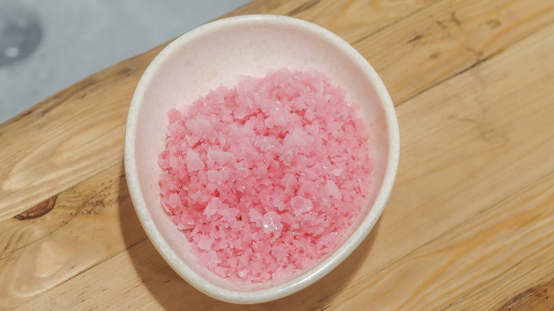 Pink Epsom salts sitting on a bathtub tray