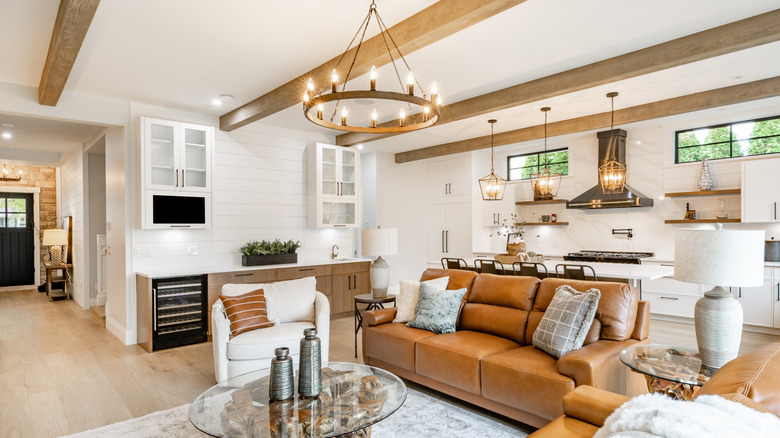 A bright, modern living room with light brown leather furniture and ceiling beams.