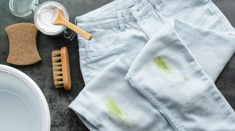 baking soda and scrub burshes on a table with grass stained pants