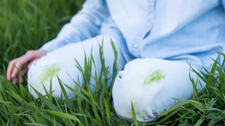 woman sitting in grass with green stains on white pants