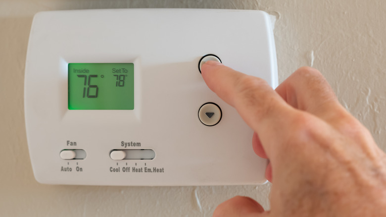Person's hand adjusting thermostat to 78 degrees
