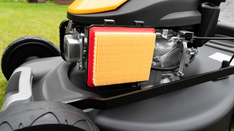 An exposed brand-new air filter on a push lawn mower.