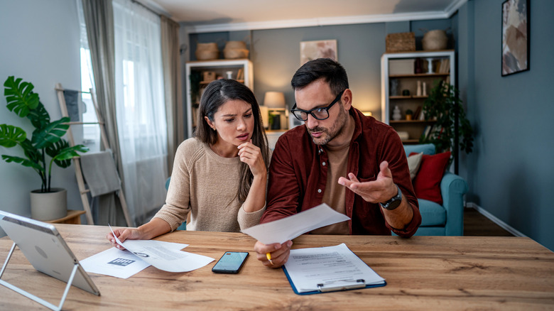 A young couple have worried expressions while looking at bills