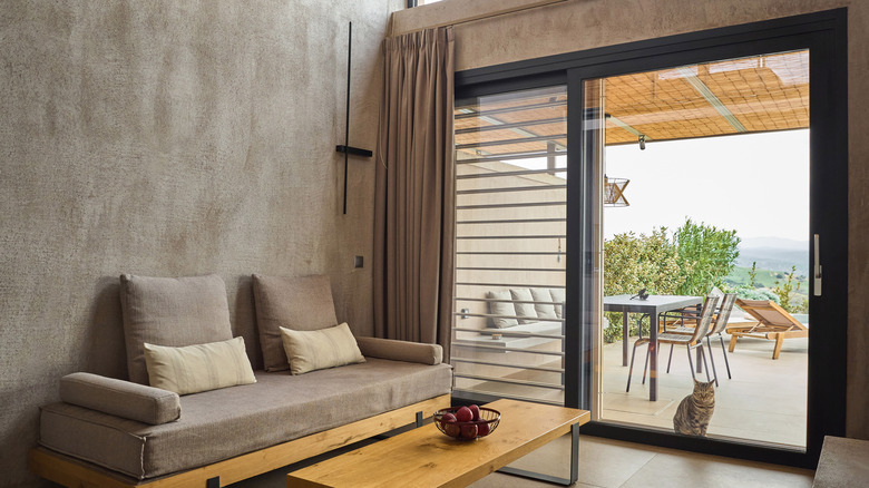 A sliding glass door separates a contemporary living room from a spacious patio