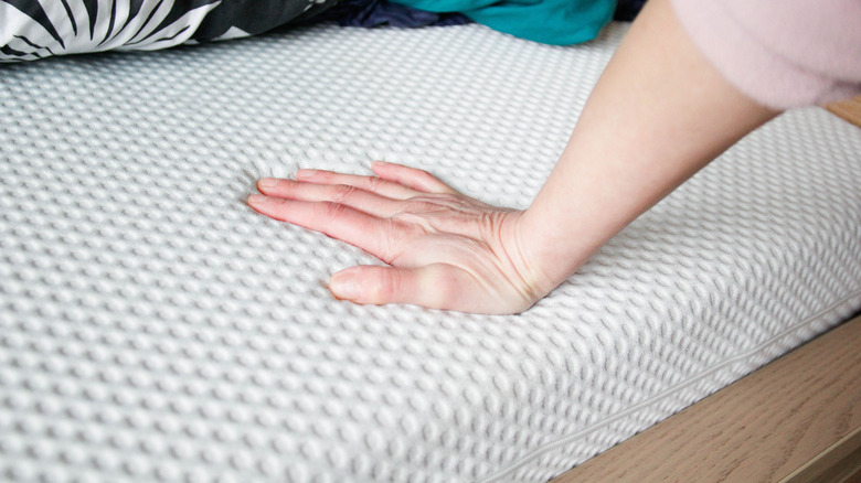 hand pressing into a foam mattress