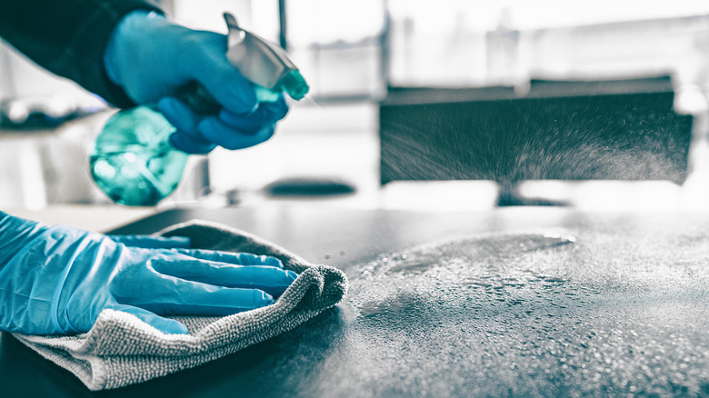 Gloved hand wiping down dirty table