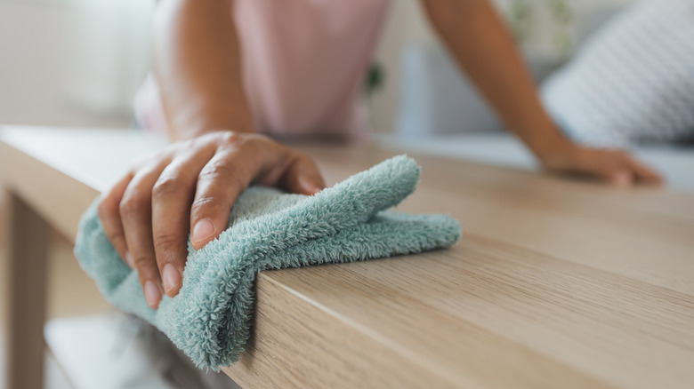 person wiping table with cloth